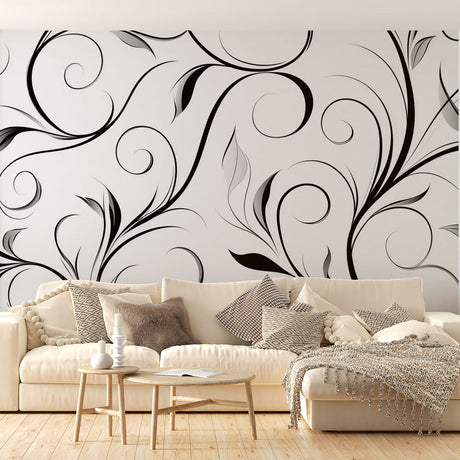 Black spiral floral wallpaper mural creating dramatic impact in a modern living room with white furniture