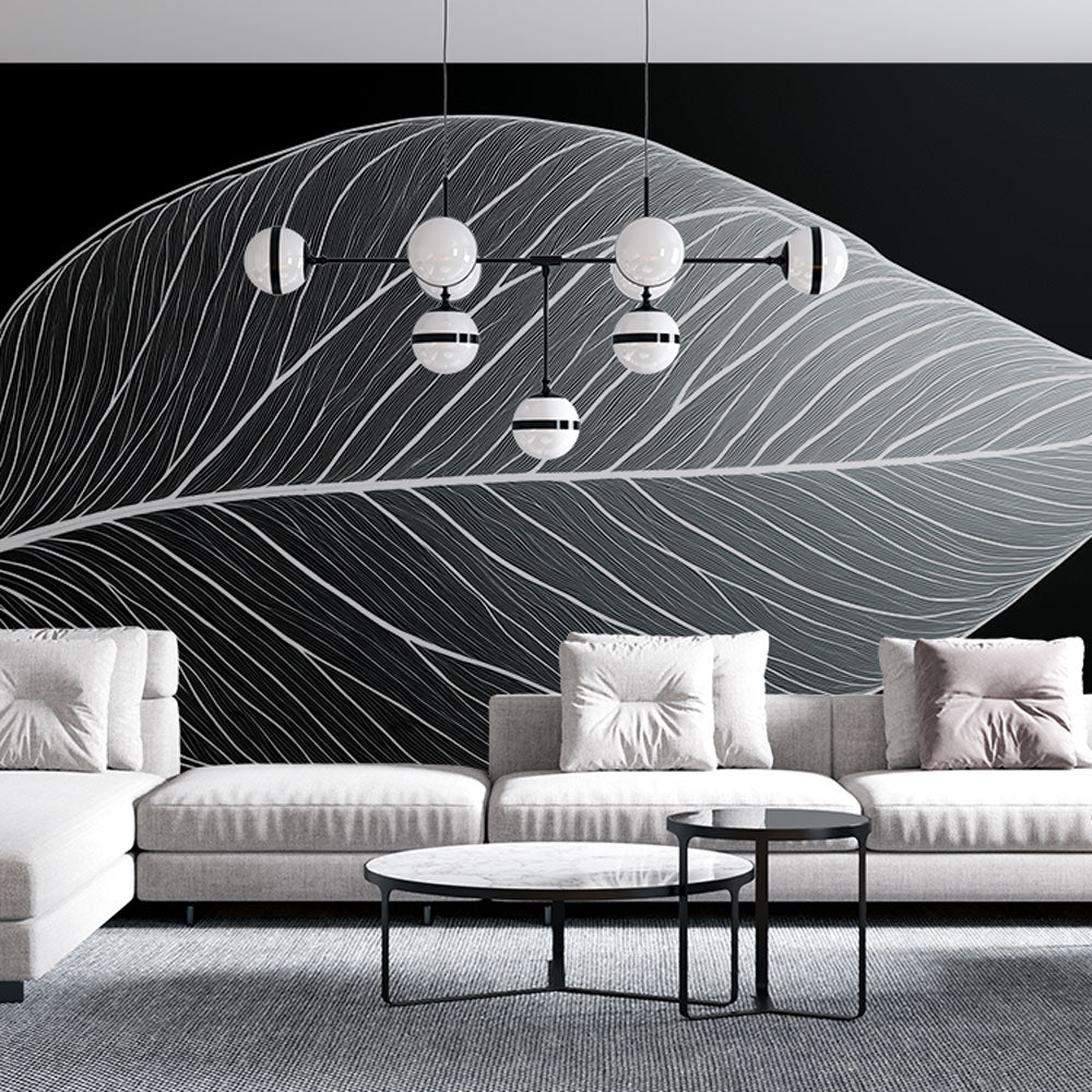 Black and white botanical leaf mural displayed in a modern living room, creating a striking monochrome feature wall