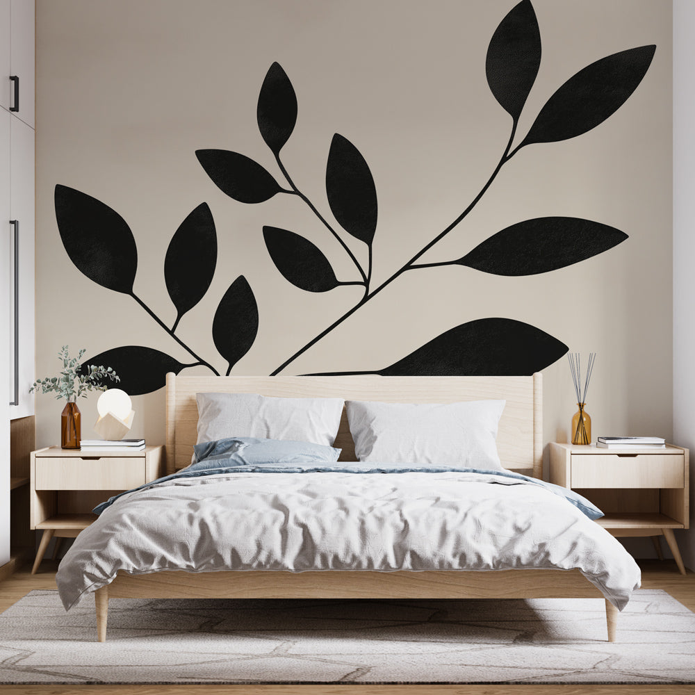 Botanical wallpaper with black leaves creating a modern statement wall in a bright living room with minimal furniture