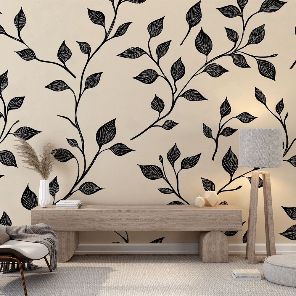 Black botanical leaf wallpaper mural in modern living room with gray sofa and natural light