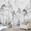 Black and white forest wallpaper mural shown in a modern living room with minimal furniture