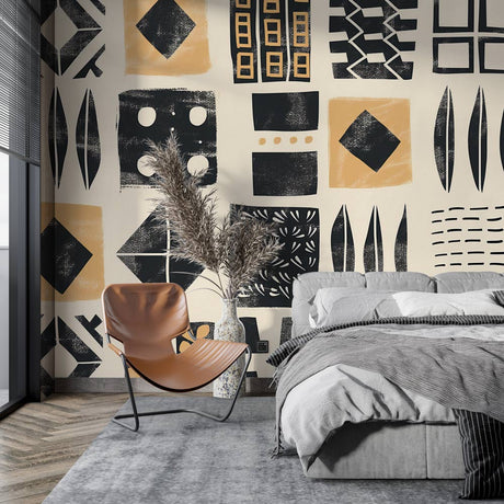 Geometric tribal wallpaper with black and gold patterns creating drama in a modern living room with minimal furniture