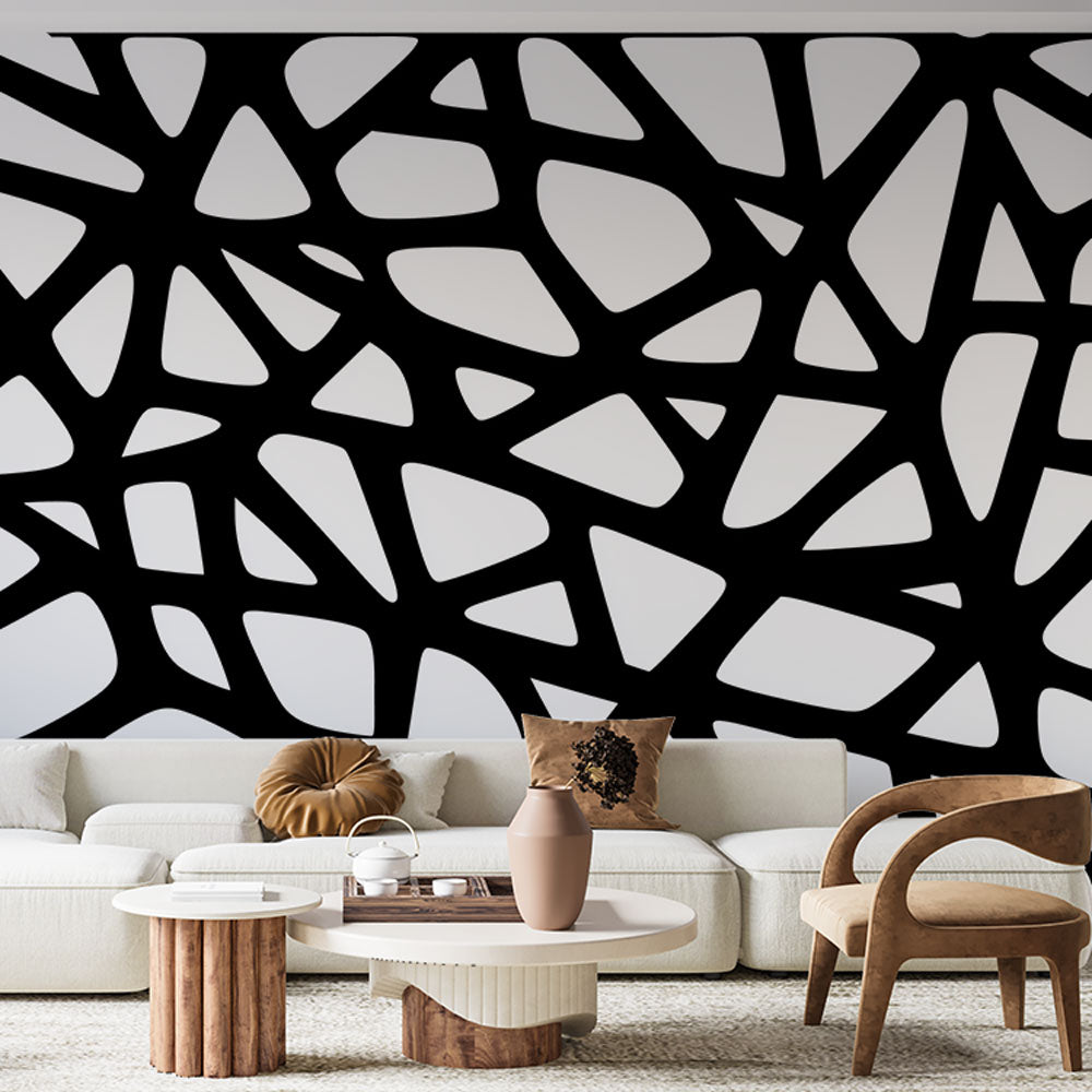 Modern geometric wallpaper creating dramatic impact in a minimalist living room with black and white furniture
