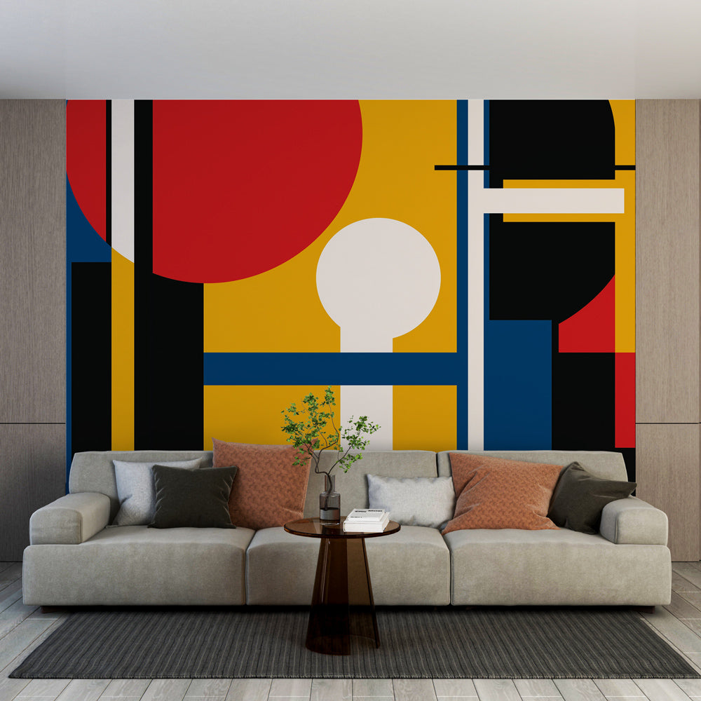Modern geometric wallpaper mural in a bright contemporary living room, showing bold Bauhaus-inspired shapes against white walls