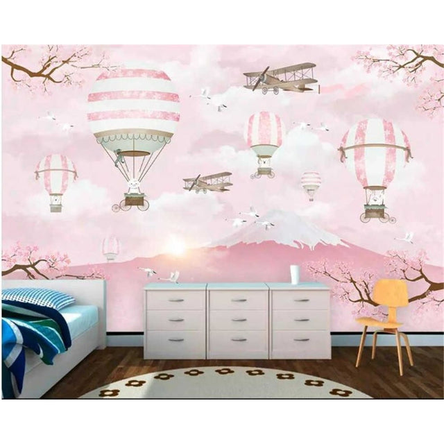Hot air balloon wallpaper creating a magical atmosphere in a bright nursery with pink accents and white furniture