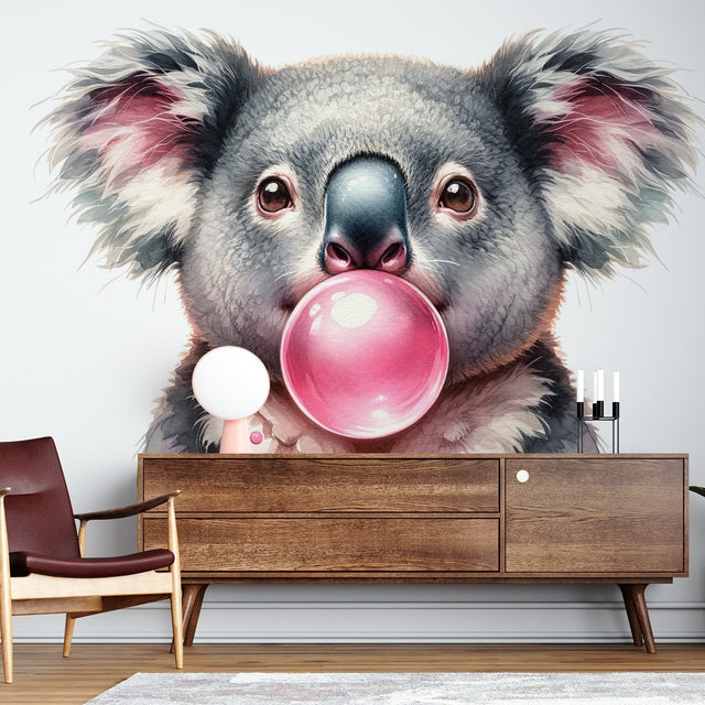 Koala wallpaper mural displayed in a bright modern nursery, showing a cute koala blowing pink bubble gum against a soft grey background