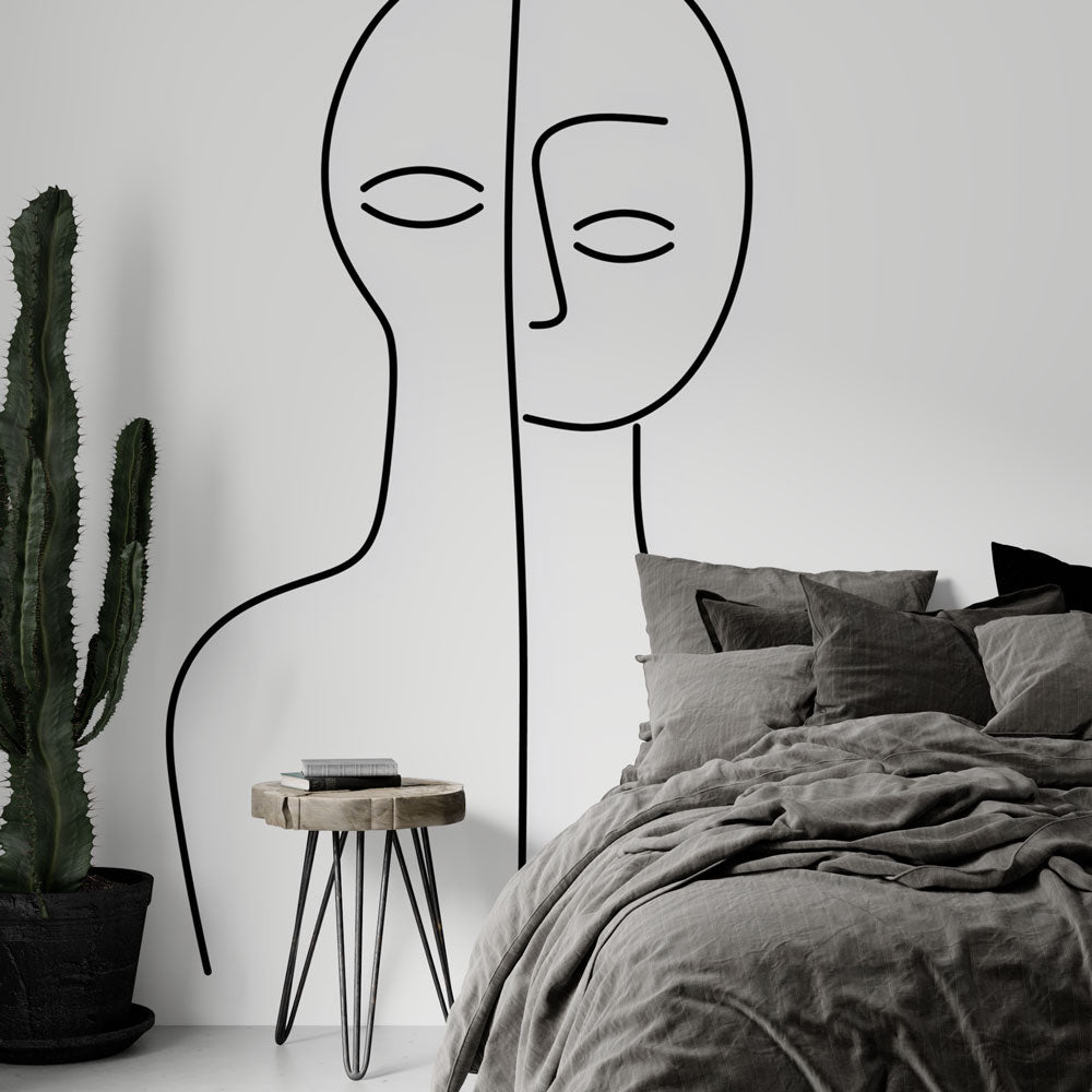Modern line art face wallpaper mural styled in a minimalist living room with grey sofa and natural light