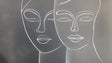 Line art face wallpaper creating a modern statement wall in a minimalist living room with grey sofa and natural light