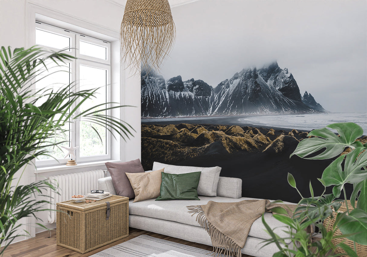 Dramatic mountain mural in minimalist bedroom with white bedding and black accents