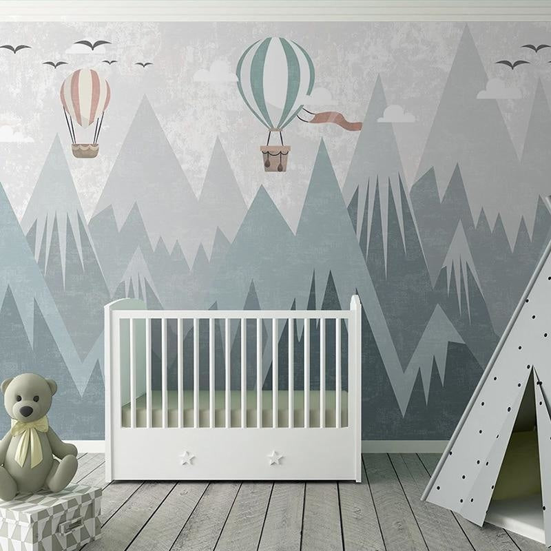 Mountain nursery wallpaper with hot air balloons shown in a bright modern nursery with white furniture
