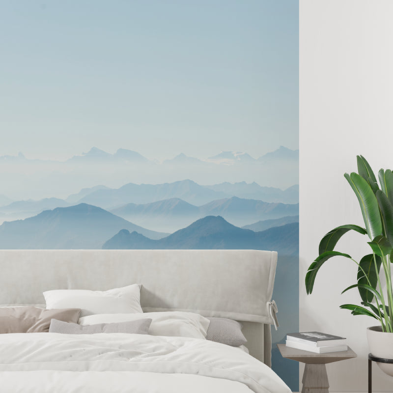Blue mountain wallpaper in peaceful bedroom setting with white bedding and wooden furniture