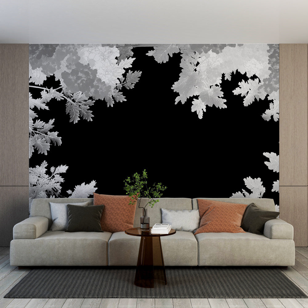 Black and white leaf pattern wallpaper in a modern living room with gray sofa and natural light