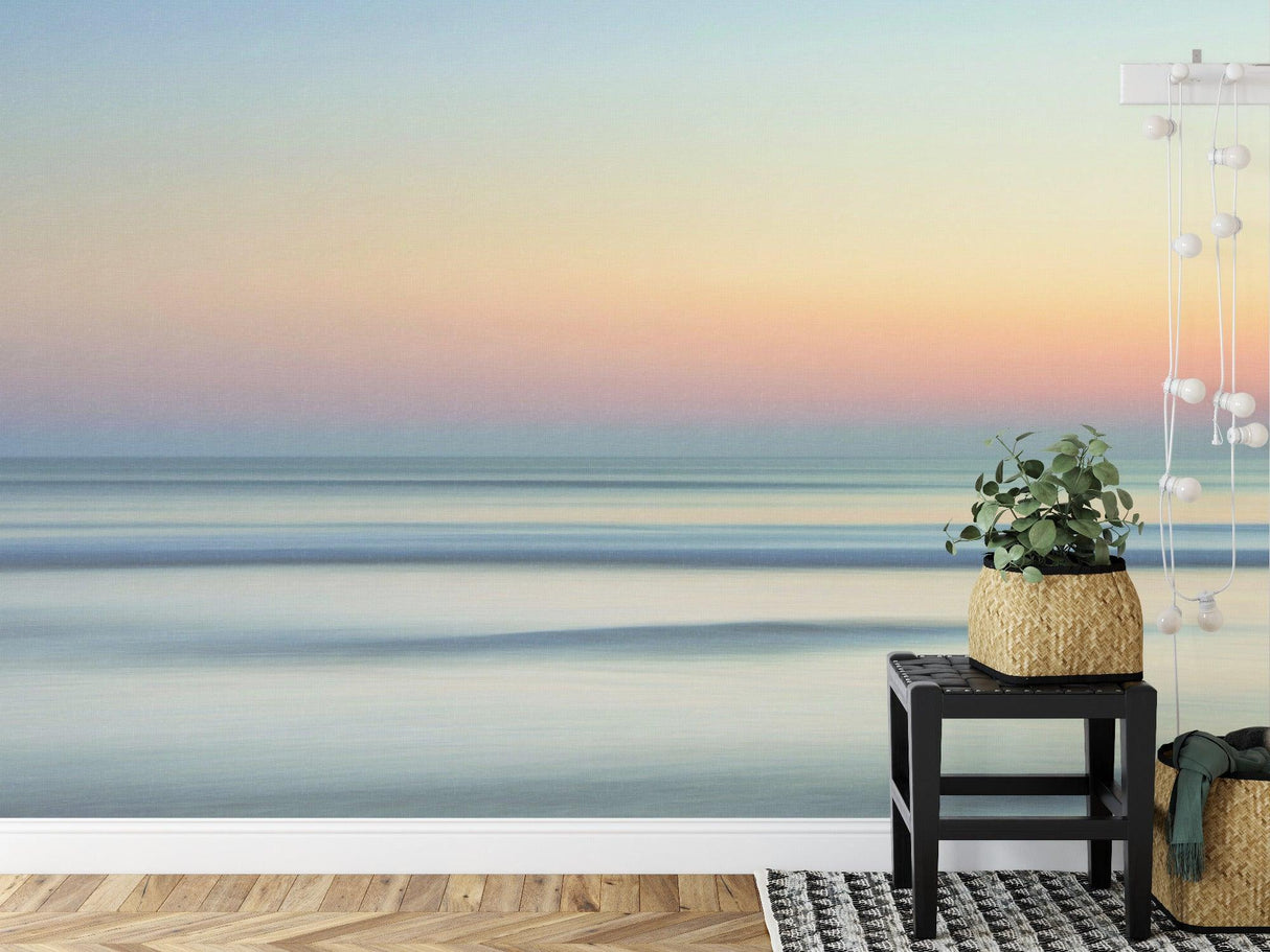 Ocean sunset wallpaper creating a calm atmosphere in a modern living room with minimal furniture