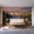 Provence landscape wallpaper with golden aqueduct scene creating depth in a modern living room with high ceilings