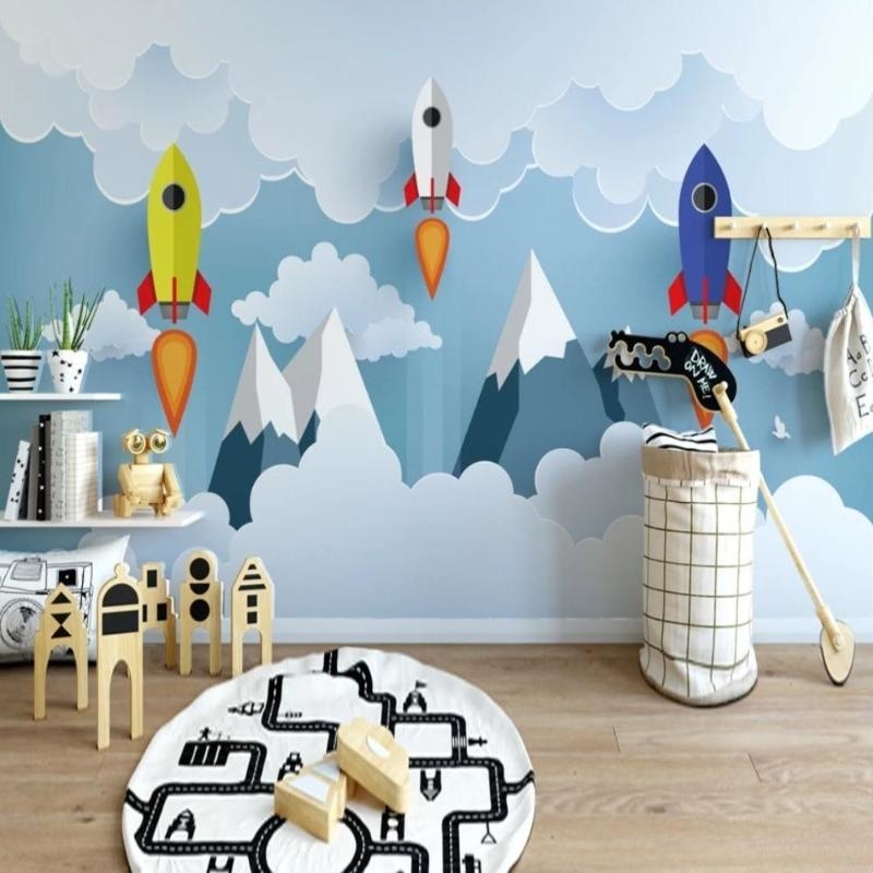 Space themed wallpaper with rockets and mountains shown in a bright modern kids bedroom with blue accents