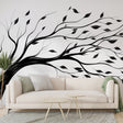 Black and white tree wallpaper creating depth in a modern minimalist living room with natural light streaming through windows