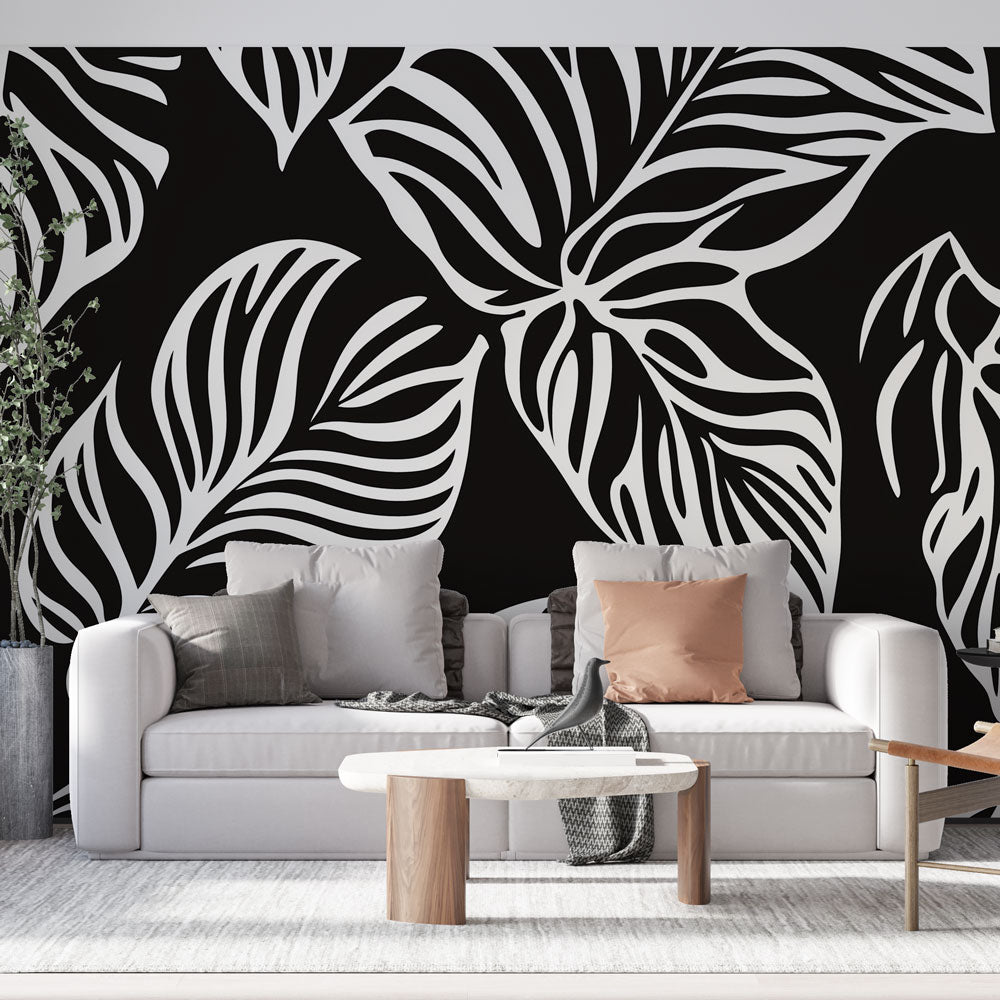 Modern black and white tropical leaf wallpaper creating dramatic contrast in a minimalist living room setting