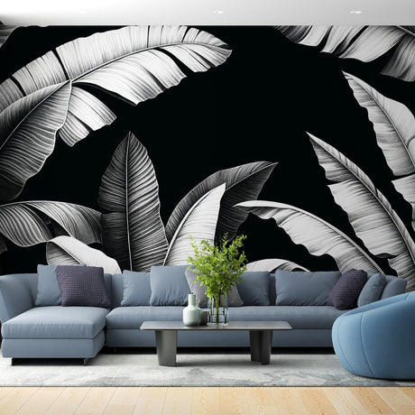 Black and white tropical leaf mural wallpaper creating drama in a modern living room with minimal furniture