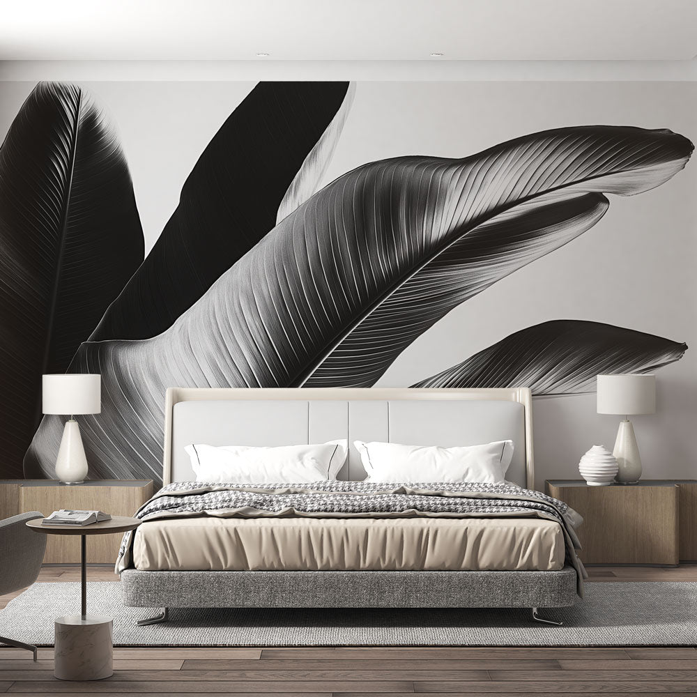 Black and white tropical leaf mural wallpaper creating drama in a modern living room with high ceilings