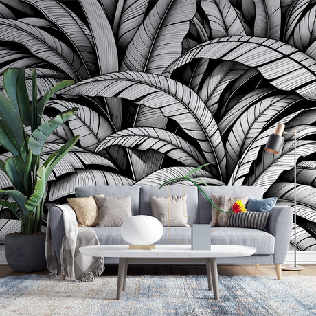 Black and white tropical leaf wallpaper creating depth in a modern living room with clean furniture and natural light