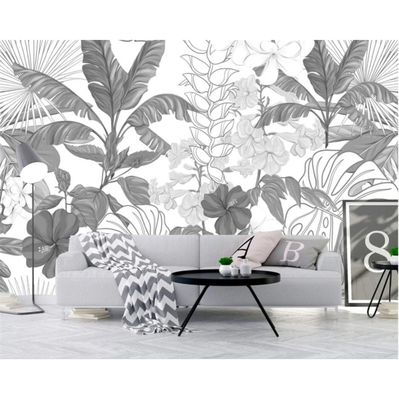Monochrome tropical wallpaper creating depth in a stylish home office with wooden desk and white accents