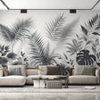 Black and white tropical leaf wallpaper creates drama in modern living room with gray sofa and natural light