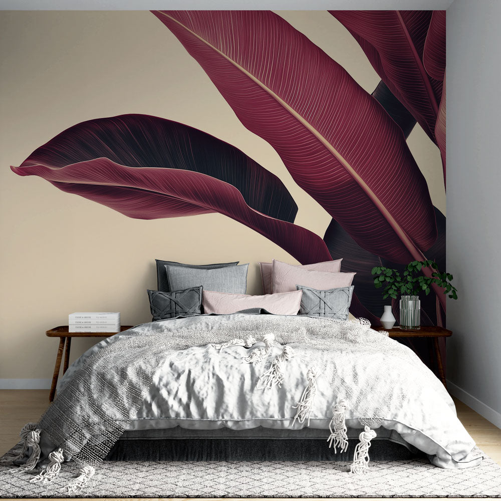 Burgundy banana leaf wallpaper creating a bold statement wall in a modern living room with grey furniture and gold accents