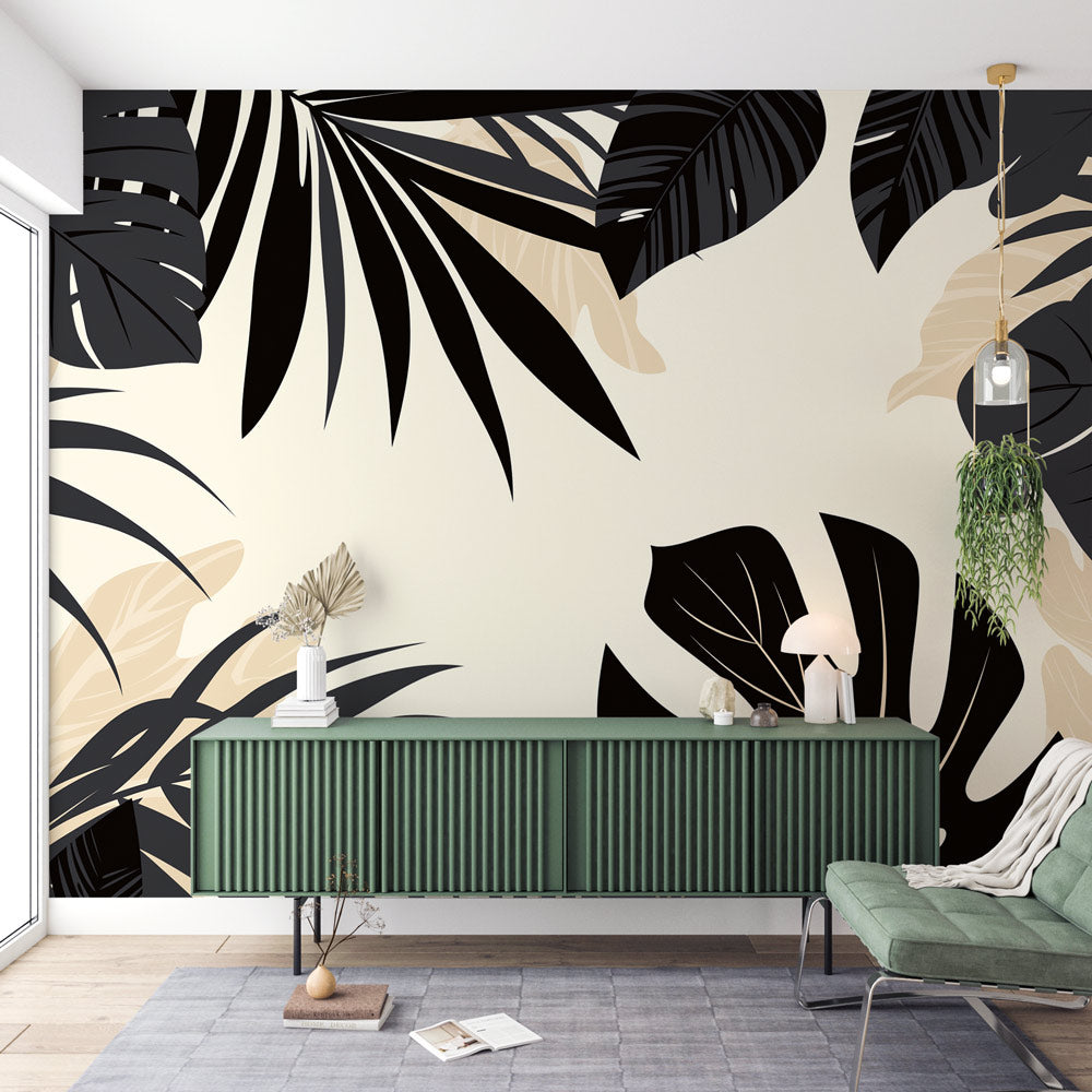 Modern black Monstera leaf wallpaper in a bright living room setting with minimal furniture and natural light