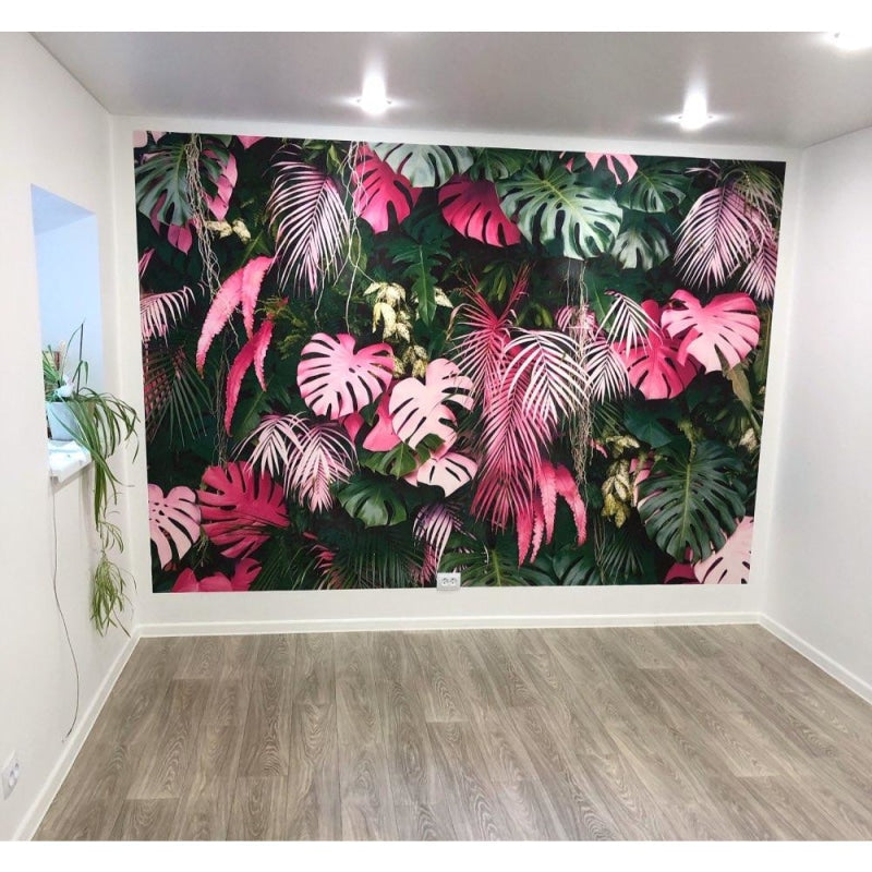 Pink and green tropical wallpaper in home office with desk and plants