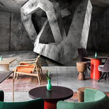 Geometric concrete wallpaper making statement in contemporary office space with glass desk and black chairs