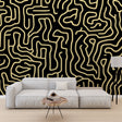 Black and gold maze pattern wallpaper creating depth in a modern living room with soft ambient lighting