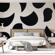 Modern abstract black curved shapes wallpaper in a minimalist living room with white sofa and natural light