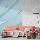 Blue and gold wave wallpaper mural creating movement in modern living room with grey sofa