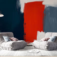 Abstract red and navy brushstroke wallpaper creating dramatic impact in a modern living room with white furniture