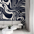 Navy and cream abstract wave wallpaper creating movement in a modern living room with gray sofa and natural light