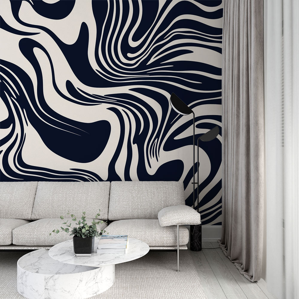 Navy and cream abstract wave wallpaper creating movement in a modern living room with gray sofa and natural light