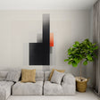 Modern geometric black and orange wallpaper in a minimalist living room with grey sofa and metal accents
