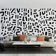 Modern abstract black and white geometric wallpaper in a minimalist living room setting with natural light