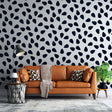 Modern black drops pattern wallpaper in a bright minimalist living room setting with clean furniture and natural light