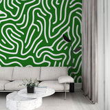 Modern green labyrinth abstract wallpaper creating depth in a bright, minimalist living room with white furniture
