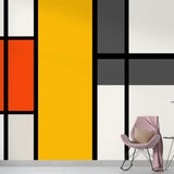 Modern geometric abstract wallpaper displayed in a bright living room, showing bold Mondrian-inspired pattern with clean lines