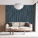 Modern teal wave wallpaper creating movement in a bright contemporary living room with minimalist furniture