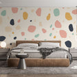 Abstract terrazzo wallpaper in soft pastels creating a modern look in a bright living room with minimal furniture