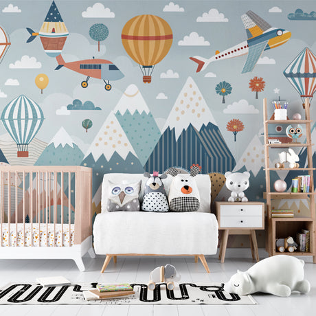 Adventure nursery wallpaper with hot air balloons and mountains styled in a modern nursery with white furniture