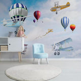 Aviation themed wallpaper in bright nursery with white furniture shows hot air balloons and vintage planes