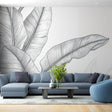 Black and white banana leaf wallpaper creating a striking focal point in a modern living room with natural light