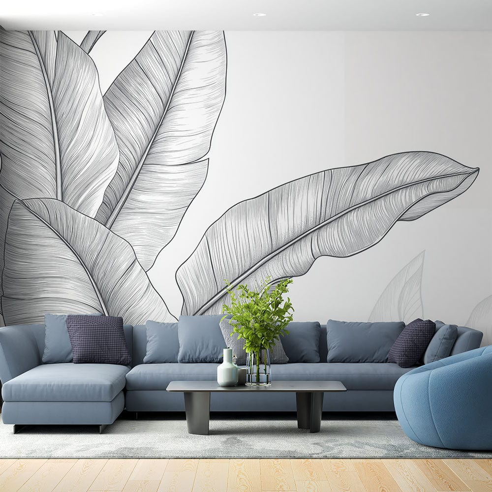 Black and white banana leaf wallpaper creating a striking focal point in a modern living room with natural light
