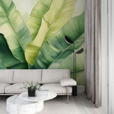 Banana leaf wallpaper creating a fresh tropical atmosphere in a modern living room with white furniture and natural light