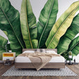 Tropical banana leaf wallpaper creating a fresh green backdrop in a modern living room with white furniture