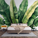 Tropical banana leaf wallpaper creating a fresh green backdrop in a modern living room with white furniture